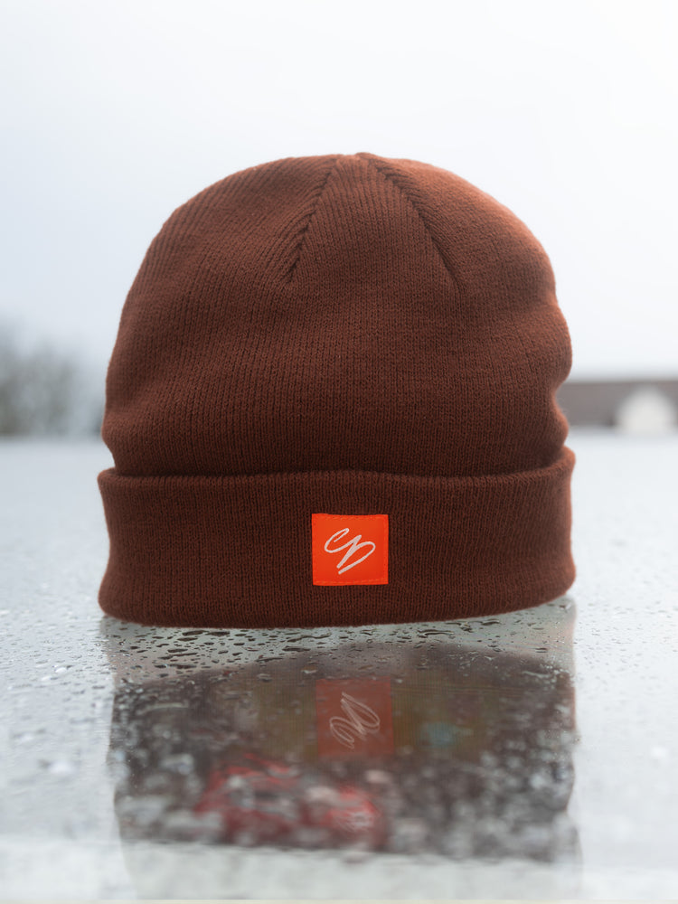 Braune Winter Beanie mit orangem Logo Patch – warme Streetwear Mütze aus 100% Acryl